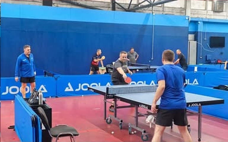 Trener prati igrače tijekom treninga za stolom